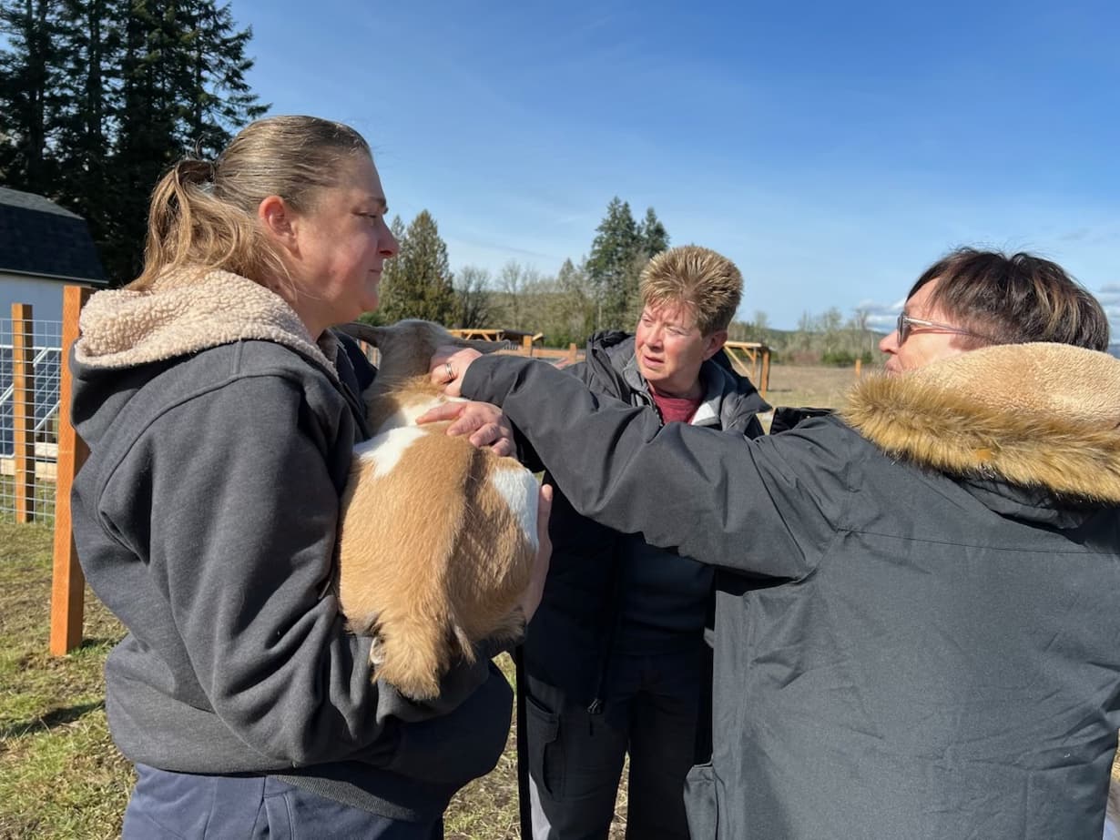 Christine holding a baby goat kid with farm visitors at RiverHouse Dairy