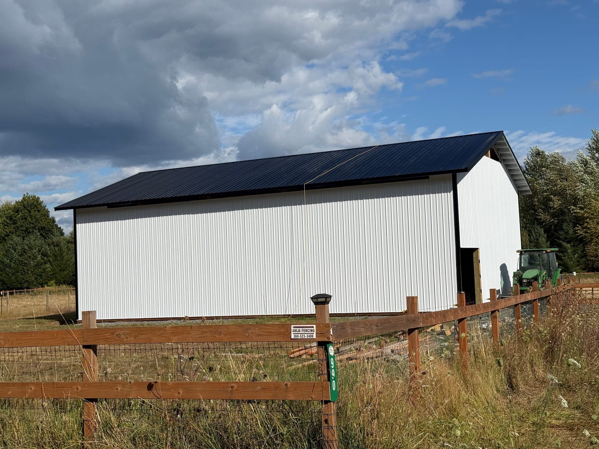 The new RiverHouse Dairy building: white metal siding with a black roof, behind a wood rail fence