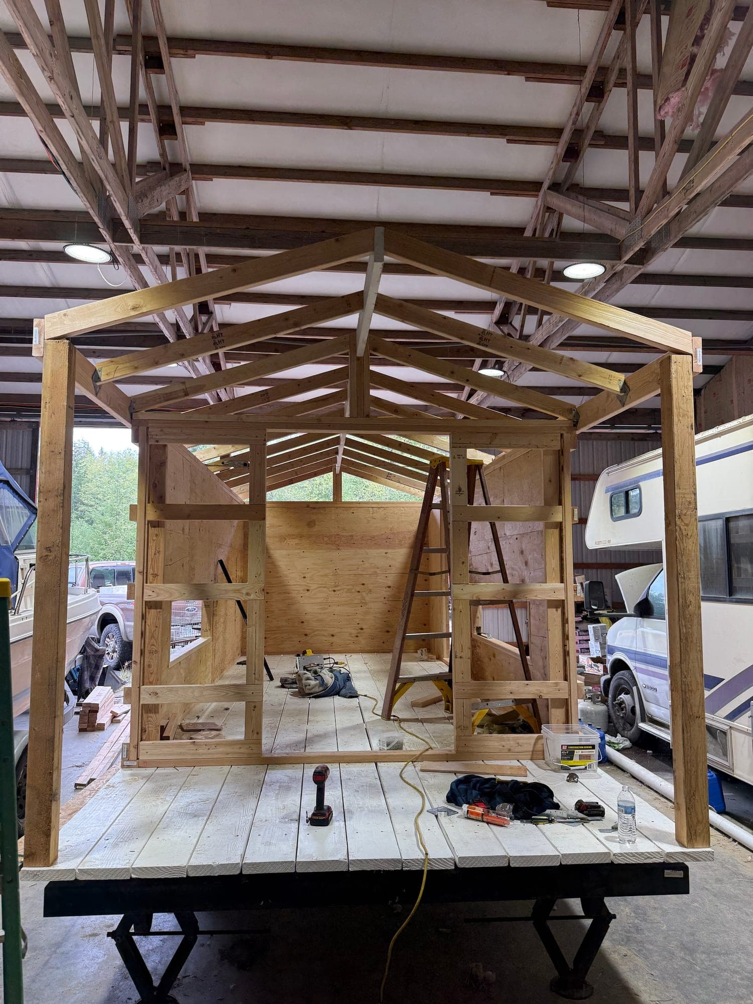 Roof trusses and porch posts framed over the plywood-walled stall