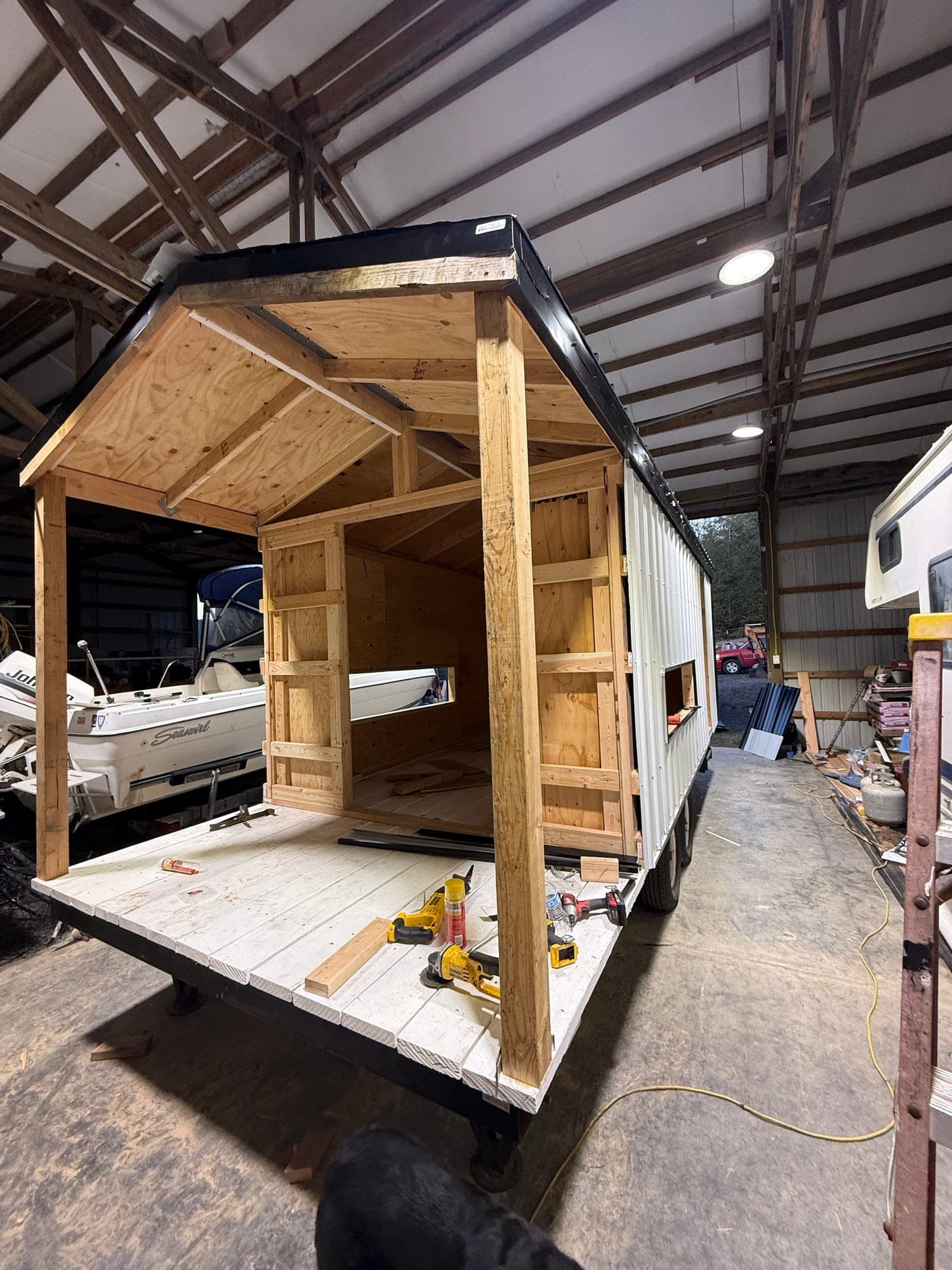 The Goat Tote with its black metal roof and white siding going on, porch framed in raw wood